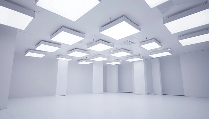 Des spots lumineux carrés sont installés sous un faux plafond tendu. Les lumières encastrées ajoutent une touche moderne et élégante, mettant en valeur la surface lisse et tendue du plafond pour un effet visuel raffiné et contemporain